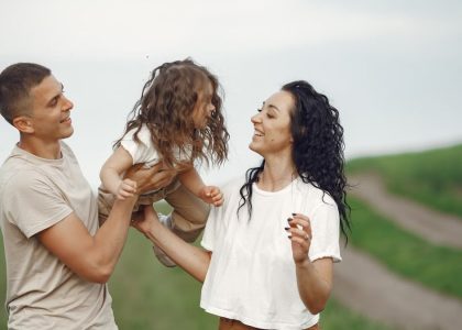 A joyful family moment outdoors with parents playing with their daughter.